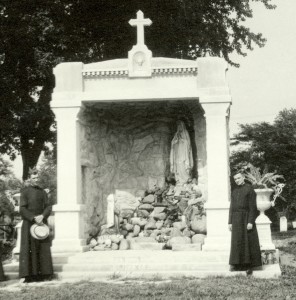 Br. John Koelzer, CSV, left, poses beside the shrine to Our Lady of Lourdes, after it was completed in 1918