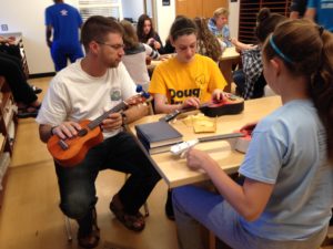 Br. John Eustice, CSV, helps a student with stringing her ukulele