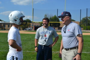 Br. Peter Lamick, center, and Fr. Dan Hall, right encourage the Lions' backup kicker