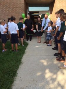 Fr. Richard Pighini, CSV, helps cut the ribbon on the new school with Principal Nicole Gernon and Superintendent Terry Granger