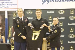 Capt. Johsua Frye, left and Staff Sgt. Christopher Spain, right, present Cole Kmet with his U.S. Army All-American Bowl jersey